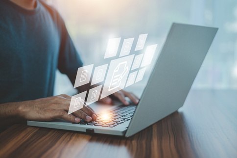 Hands at a laptop with floating document icons
